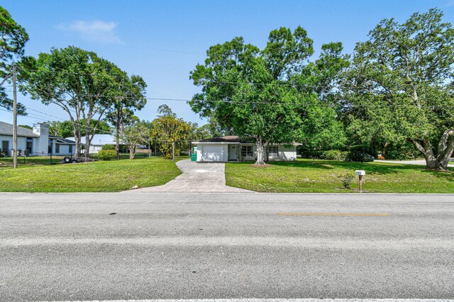 6506 Kings Hwy, Fort Pierce, FL 34951 - view of front of house with concrete driveway, a front lawn, and a garage