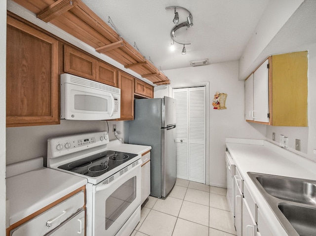 815 W Boynton Beach Blvd Unit 15-203, Boynton Beach, FL 33426 - kitchen with white appliances, light countertops, light tile patterned floors, brown cabinetry, and a sink