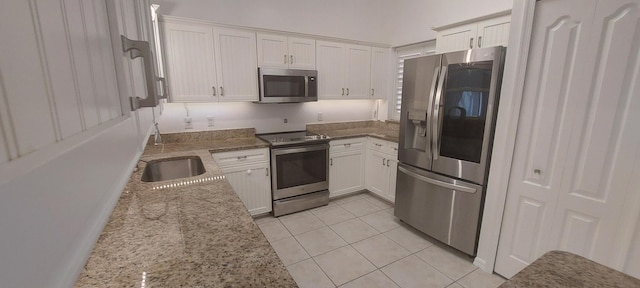 456 NW Marsala Ter, Port Saint Lucie, FL 34986 - kitchen featuring appliances with stainless steel finishes, white cabinetry, light stone countertops, light tile patterned floors, and a sink