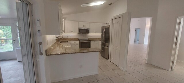 456 NW Marsala Ter, Port Saint Lucie, FL 34986 - kitchen featuring appliances with stainless steel finishes, light tile patterned floors, stone counters, white cabinetry, and vaulted ceiling