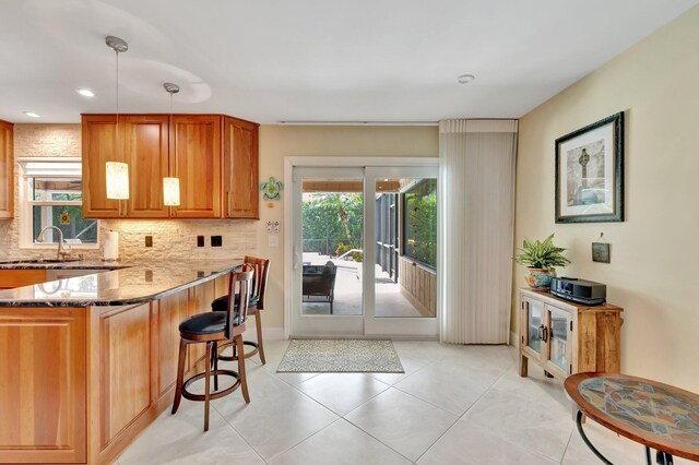 519 SE Brookside Ter, Port Saint Lucie, FL 34983 - kitchen with stone counters, backsplash, a breakfast bar, a sink, and light tile patterned floors