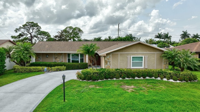 519 SE Brookside Ter, Port Saint Lucie, FL 34983 - ranch-style house with stone siding, a front lawn, driveway, stucco siding, and roof with shingles