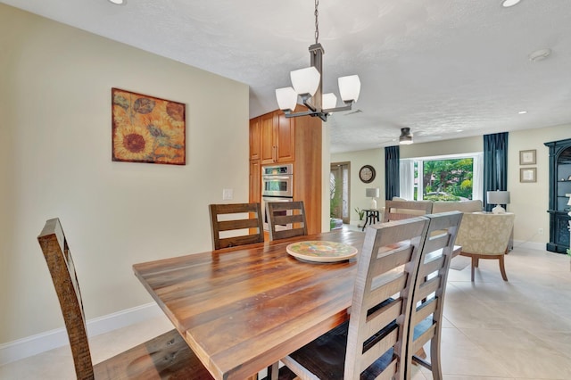 519 SE Brookside Ter, Port Saint Lucie, FL 34983 - dining room featuring a chandelier, baseboards, a textured ceiling, ceiling fan, and light tile patterned floors