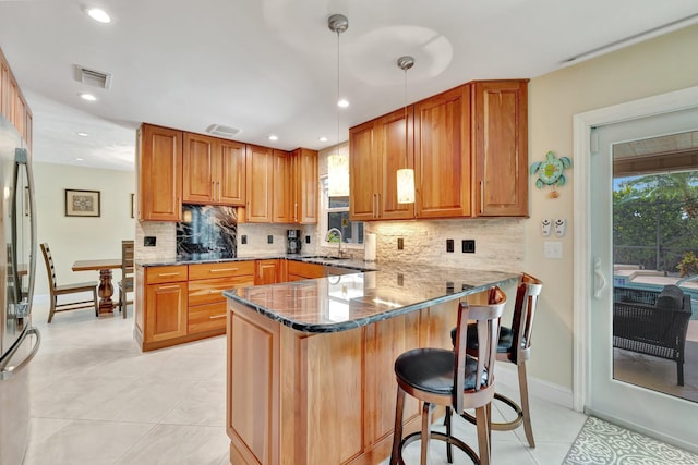 519 SE Brookside Ter, Port Saint Lucie, FL 34983 - kitchen with dark stone countertops, a breakfast bar, tasteful backsplash, a peninsula, and recessed lighting