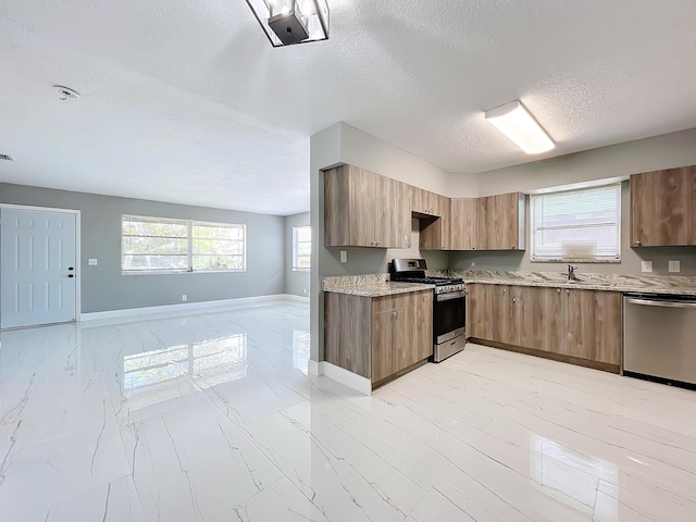 903 21st St, West Palm Beach, FL 33407 - kitchen featuring stainless steel appliances, open floor plan, a textured ceiling, light marble finish floors, and modern cabinets