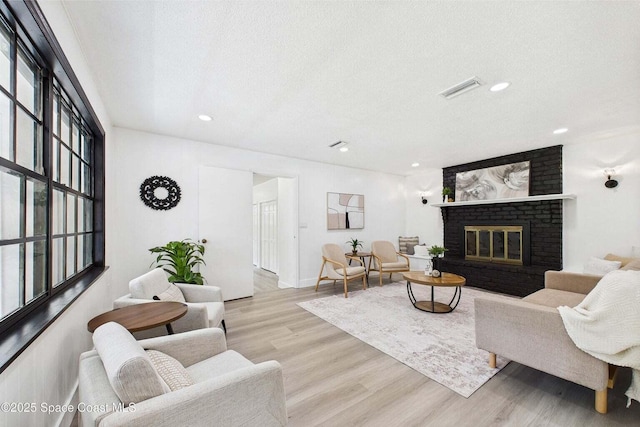 2318 Old Samsula Rd, Port Orange, FL 32128 - living room featuring a textured ceiling, light wood-style floors, a fireplace, and recessed lighting
