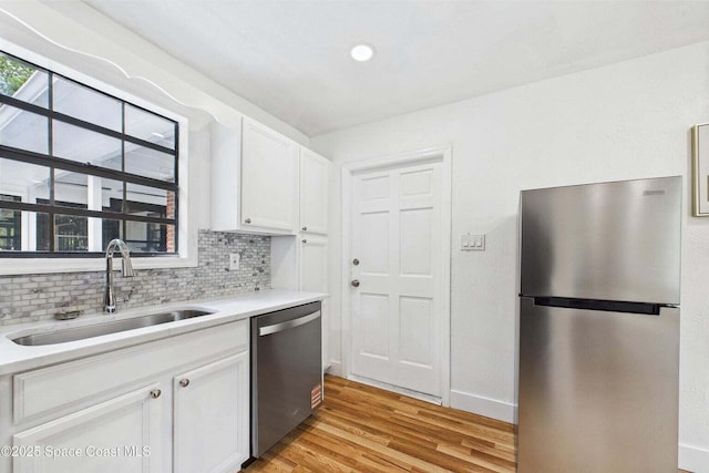 2318 Old Samsula Rd, Port Orange, FL 32128 - kitchen featuring appliances with stainless steel finishes, a sink, light wood finished floors, white cabinetry, and light countertops