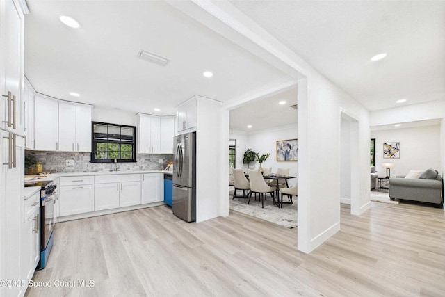 2318 Old Samsula Rd, Port Orange, FL 32128 - kitchen with appliances with stainless steel finishes, light wood finished floors, white cabinets, tasteful backsplash, and recessed lighting