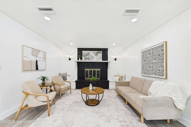 2318 Old Samsula Rd, Port Orange, FL 32128 - living area featuring wood finished floors, baseboards, a brick fireplace, a textured ceiling, and recessed lighting