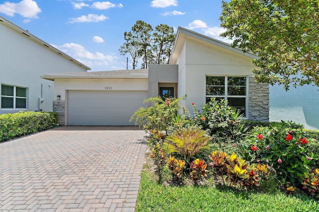 6825 Pointe Of Woods Dr, West Palm Beach, FL 33413 - view of front of house featuring stucco siding, a garage, decorative driveway, and stone siding