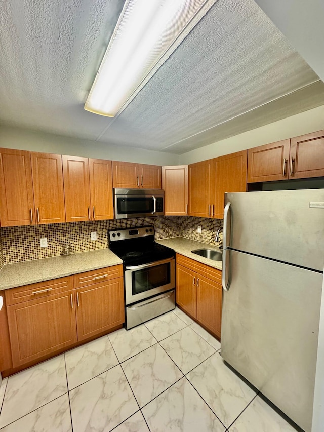 200 Village Green Cir E Unit 102, Palm Springs, FL 33461 - kitchen featuring stainless steel appliances, light marble finish flooring, a sink, brown cabinetry, and tasteful backsplash
