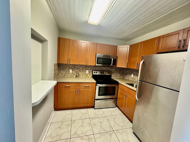 200 Village Green Cir E Unit 102, Palm Springs, FL 33461 - kitchen featuring stainless steel appliances, light marble finish flooring, tasteful backsplash, light countertops, and a textured ceiling