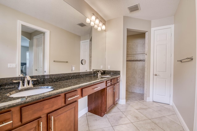 10295 SW Waterway Ln, Port Saint Lucie, FL 34987 - bathroom featuring double vanity, tile patterned floors, a textured ceiling, and tiled shower
