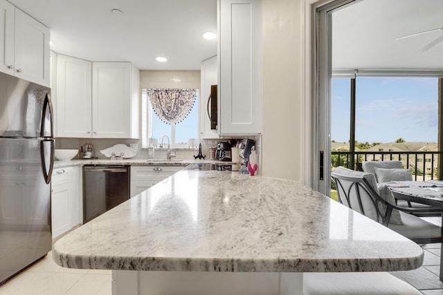275 Palm Ave Unit A406, Jupiter, FL 33477 - kitchen with appliances with stainless steel finishes, light stone countertops, white cabinetry, light tile patterned flooring, and a kitchen island