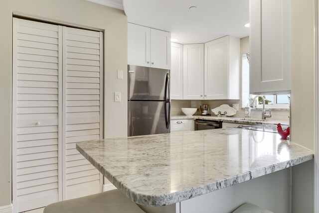 275 Palm Ave Unit A406, Jupiter, FL 33477 - kitchen featuring freestanding refrigerator, a peninsula, light stone counters, a breakfast bar area, and white cabinets