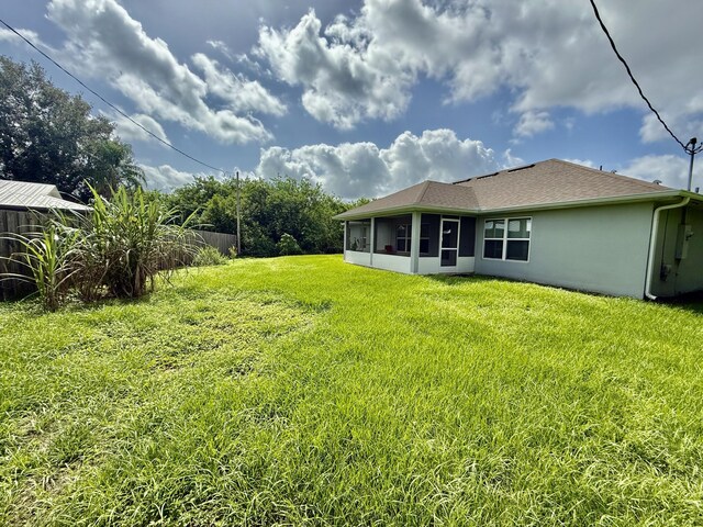 4480 SW Jaunt Rd, Port Saint Lucie, FL 34953 - back of house featuring a sunroom, stucco siding, a yard, and roof with shingles