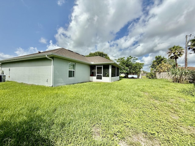 4480 SW Jaunt Rd, Port Saint Lucie, FL 34953 - rear view of property with a sunroom, stucco siding, a lawn, cooling unit, and roof with shingles