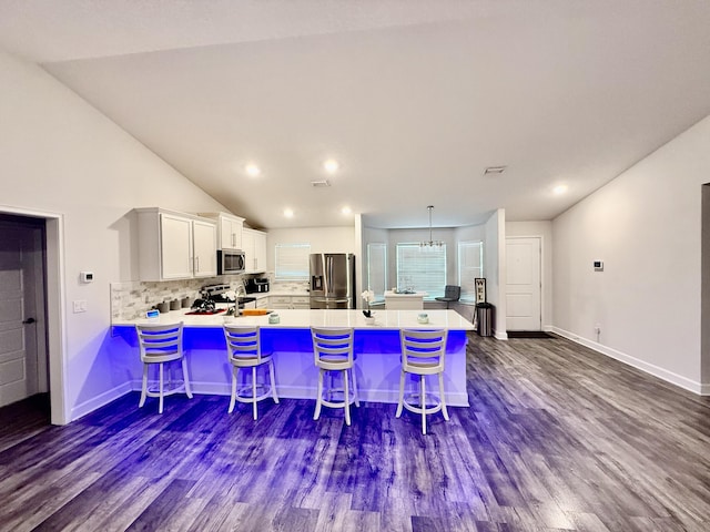 4480 SW Jaunt Rd, Port Saint Lucie, FL 34953 - kitchen with stainless steel appliances, a peninsula, white cabinets, backsplash, and a breakfast bar