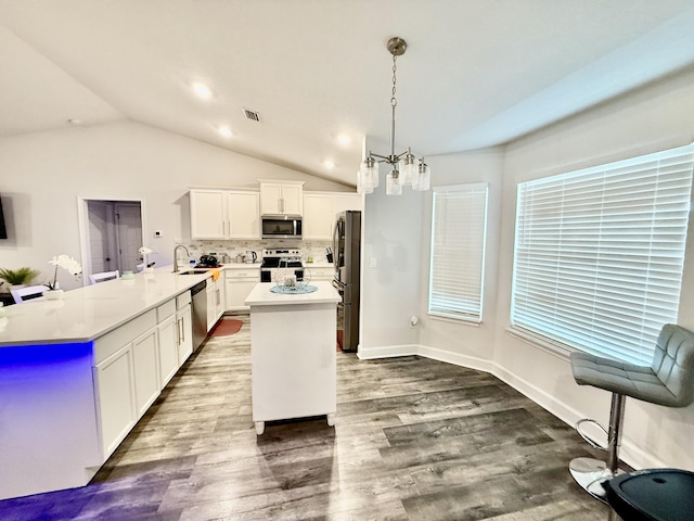 4480 SW Jaunt Rd, Port Saint Lucie, FL 34953 - kitchen featuring appliances with stainless steel finishes, a peninsula, vaulted ceiling, a kitchen island, and tasteful backsplash