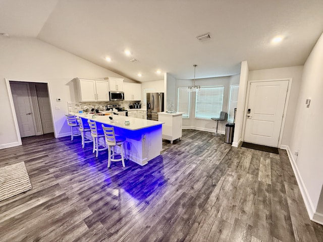 4480 SW Jaunt Rd, Port Saint Lucie, FL 34953 - kitchen with stainless steel appliances, a peninsula, white cabinets, dark wood-type flooring, and a breakfast bar area