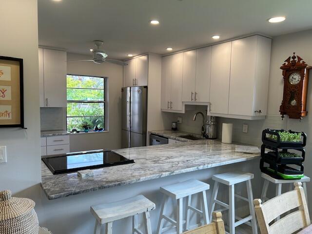 100 Lake Terry Dr, West Palm Beach, FL 33411 - kitchen featuring freestanding refrigerator, a sink, a peninsula, tasteful backsplash, and recessed lighting