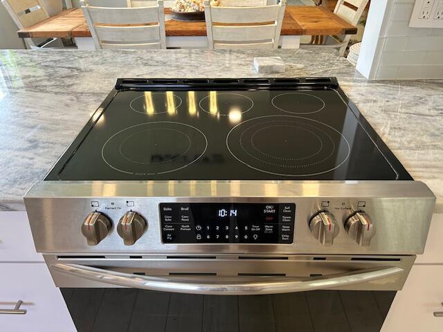 100 Lake Terry Dr, West Palm Beach, FL 33411 - kitchen view of stainless steel range with electric stovetop, tasteful backsplash, and light stone counters