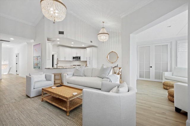 402 Sea Oats Dr Unit F, Juno Beach, FL 33408 - living room with crown molding, light wood-style floors, french doors, a chandelier, and a towering ceiling