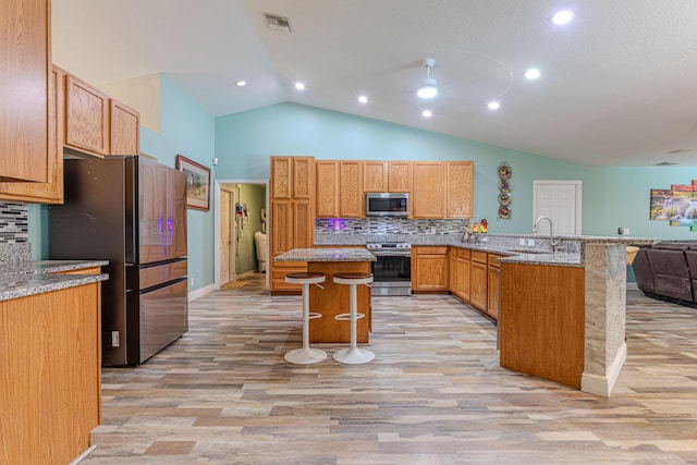 16330 Wiltshire Dr E, Loxahatchee, FL 33470 - kitchen featuring appliances with stainless steel finishes, a breakfast bar, open floor plan, a peninsula, and lofted ceiling