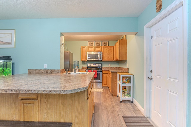 16330 Wiltshire Dr E, Loxahatchee, FL 33470 - kitchen featuring stainless steel appliances, light wood-style floors, a peninsula, light countertops, and a textured ceiling