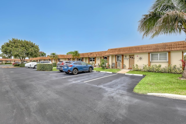 5780 W Fernley Dr Unit 101, West Palm Beach, FL 33415 - view of front of home with uncovered parking, stucco siding, a front lawn, and a tile roof