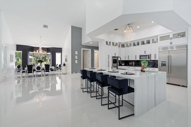 8076 Twin Lake Dr, Boca Raton, FL 33496 - kitchen with appliances with stainless steel finishes, a chandelier, white cabinetry, a spacious island, and a kitchen breakfast bar