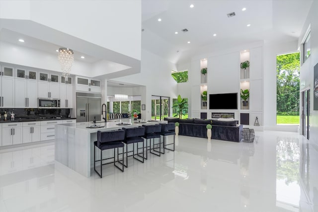 8076 Twin Lake Dr, Boca Raton, FL 33496 - kitchen featuring stainless steel appliances, light tile patterned floors, a chandelier, recessed lighting, and a kitchen breakfast bar