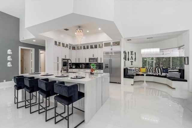 8076 Twin Lake Dr, Boca Raton, FL 33496 - kitchen featuring stainless steel appliances, light tile patterned flooring, white cabinets, a kitchen breakfast bar, and recessed lighting