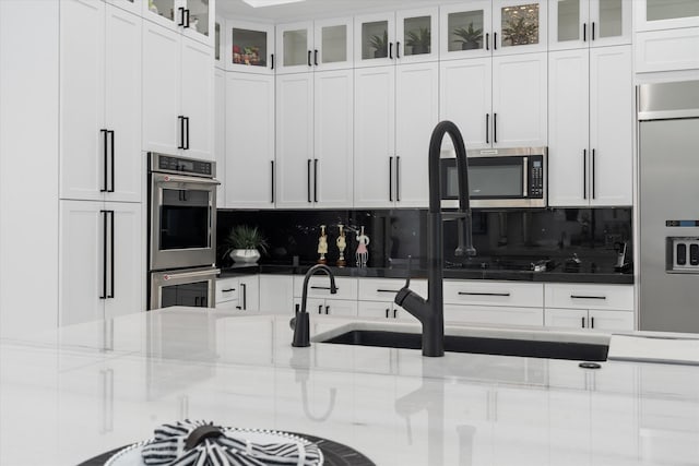 8076 Twin Lake Dr, Boca Raton, FL 33496 - kitchen featuring stainless steel appliances, tasteful backsplash, white cabinets, and glass insert cabinets