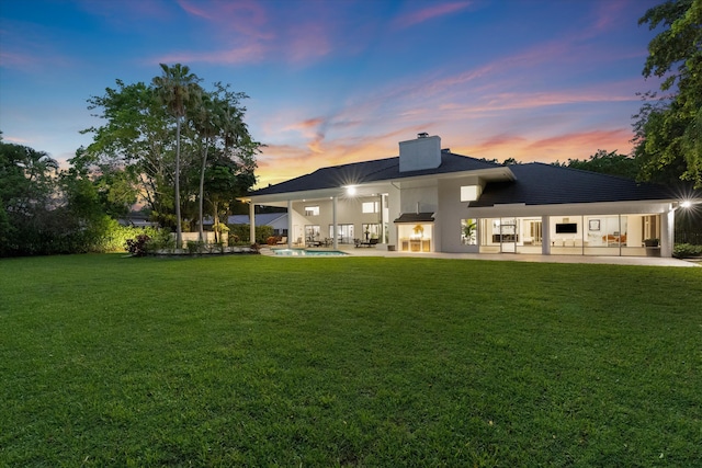 8076 Twin Lake Dr, Boca Raton, FL 33496 - back of property at dusk featuring a chimney, a patio, a lawn, and an outdoor pool