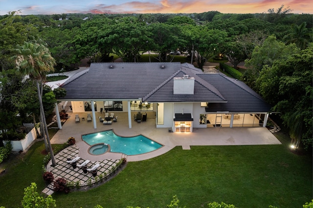 8076 Twin Lake Dr, Boca Raton, FL 33496 - back of property at dusk with a patio, a pool with connected hot tub, stucco siding, and a tiled roof