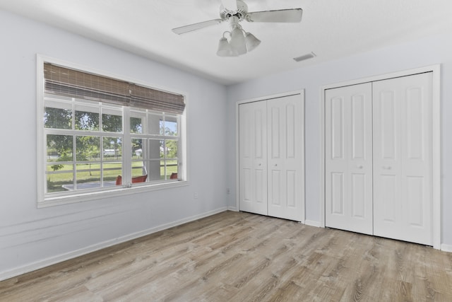 14685 40th St N, Loxahatchee Groves, FL 33470 - unfurnished bedroom featuring multiple closets, light wood-style floors, baseboards, and ceiling fan