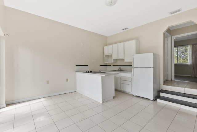 14685 40th St N, Loxahatchee Groves, FL 33470 - kitchen with freestanding refrigerator, white cabinetry, a peninsula, arched walkways, and light countertops