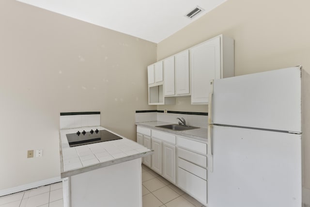 14685 40th St N, Loxahatchee Groves, FL 33470 - kitchen with freestanding refrigerator, a sink, black electric cooktop, tile counters, and white cabinets