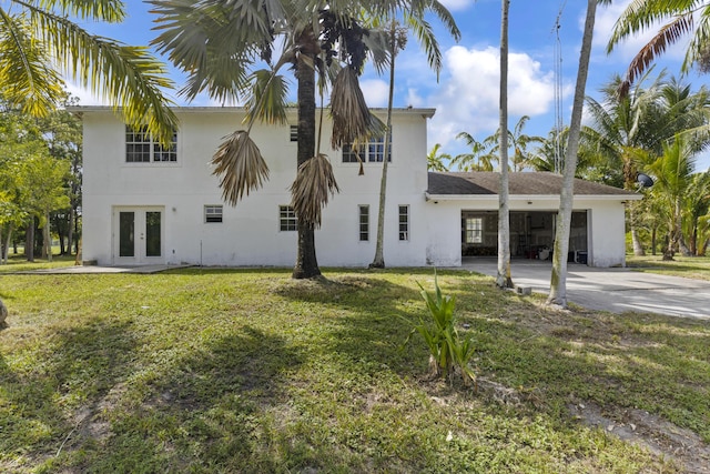 14685 40th St N, Loxahatchee Groves, FL 33470 - back of house featuring french doors, stucco siding, concrete driveway, and a lawn