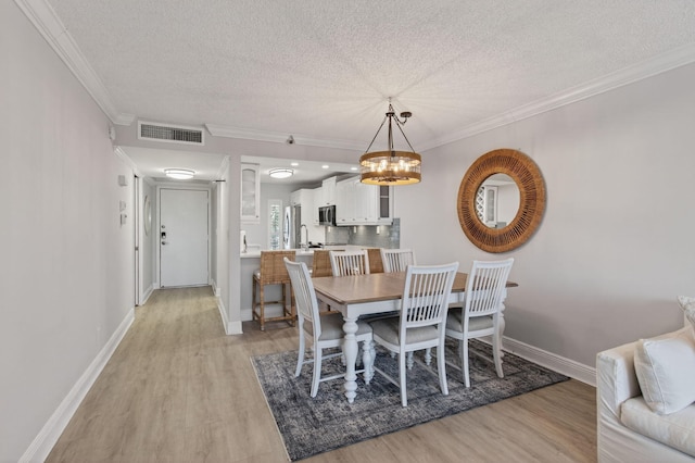 22 Royal Palm Way Unit 205, Boca Raton, FL 33432 - dining space featuring a textured ceiling, a chandelier, light wood-style floors, and crown molding