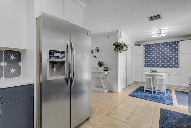 9277 Bloomfield Dr, Palm Beach Gardens, FL 33410 - kitchen featuring stainless steel fridge, crown molding, light tile patterned flooring, white cabinetry, and light countertops