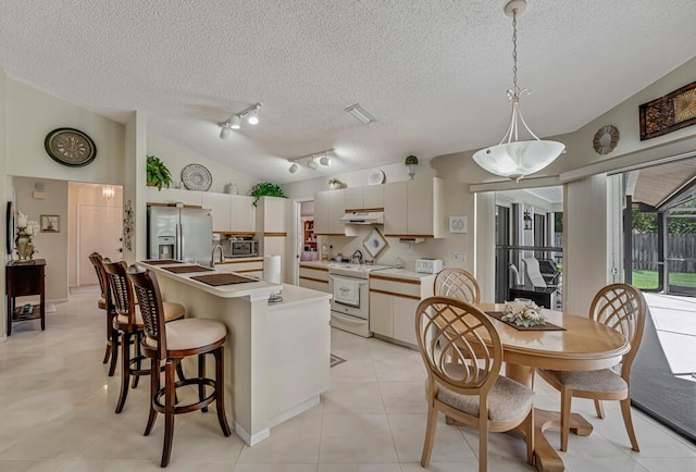 1500 Chapparel Way, Wellington, FL 33414 - kitchen featuring appliances with stainless steel finishes, under cabinet range hood, a textured ceiling, light countertops, and a breakfast bar
