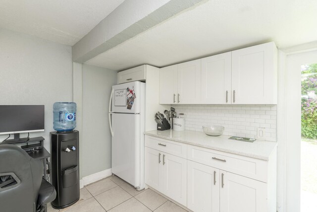 4337 Clinton Blvd, Lake Worth, FL 33461 - kitchen featuring freestanding refrigerator, tasteful backsplash, white cabinets, light tile patterned flooring, and light stone countertops
