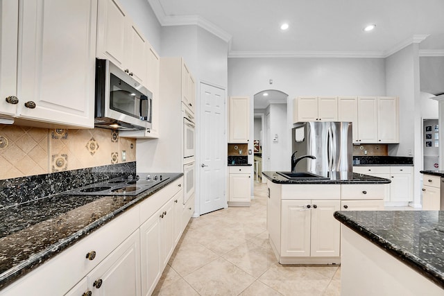 4450 SW Long Bay Dr, Palm City, FL 34990 - kitchen featuring stainless steel appliances, crown molding, arched walkways, a sink, and decorative backsplash