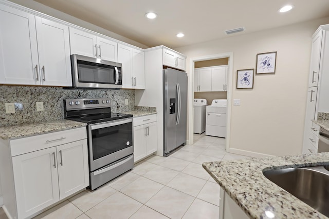2 Tosca, Fort Pierce, FL 34951 - kitchen with stainless steel appliances, independent washer and dryer, white cabinets, tasteful backsplash, and light tile patterned floors
