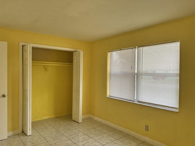 5042 Eadie Pl, West Palm Beach, FL 33407 - unfurnished bedroom featuring a closet, baseboards, and light tile patterned flooring