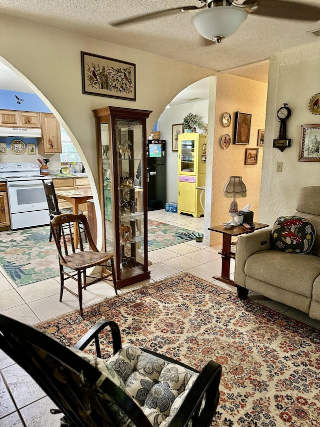 3595 SW 19th St, Okeechobee, FL 34974 - living area featuring arched walkways, a textured ceiling, a textured wall, light tile patterned flooring, and a ceiling fan