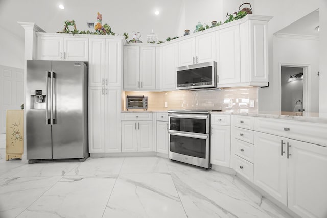 1680 SW 16th St, Boca Raton, FL 33486 - kitchen featuring appliances with stainless steel finishes, ornamental molding, white cabinets, tasteful backsplash, and light marble finish floors