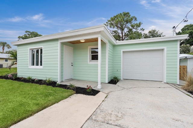 677 NE Alice St, Jensen Beach, FL 34957 - view of front facade featuring concrete driveway, a front yard, and an attached garage